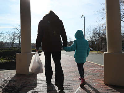 A woman and her daughter walk from her elementary school after picking up her breakfast and lunch in Revere, Massachusetts, on December 11, 2020.
