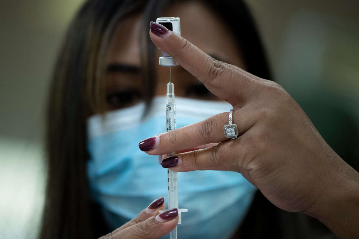 A pharmacist dilutes the Pfizer COVID-19 vaccine while preparing it to administer to staff and residents at the Goodwin House Bailey's Crossroads, a senior living community in Falls Church, Virginia, on December 30, 2020.