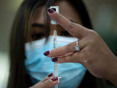 A pharmacist dilutes the Pfizer COVID-19 vaccine while preparing it to administer to staff and residents at the Goodwin House Bailey's Crossroads, a senior living community in Falls Church, Virginia, on December 30, 2020.