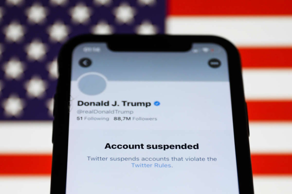 Donald Trump's Twitter account displayed on a phone screen and American flag in the background on January 9, 2021.