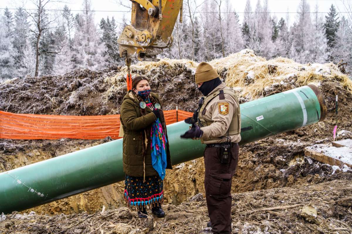 An Indigenous Water Protector and an Aitkin County sheriff chat in front of a construction site for the Line 3 tar sands pipeline near Palisade, Minnesota, on January 9, 2021.