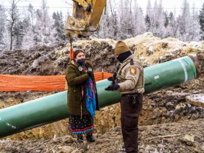 An Indigenous Water Protector and an Aitkin County sheriff chat in front of a construction site for the Line 3 tar sands pipeline near Palisade, Minnesota, on January 9, 2021.