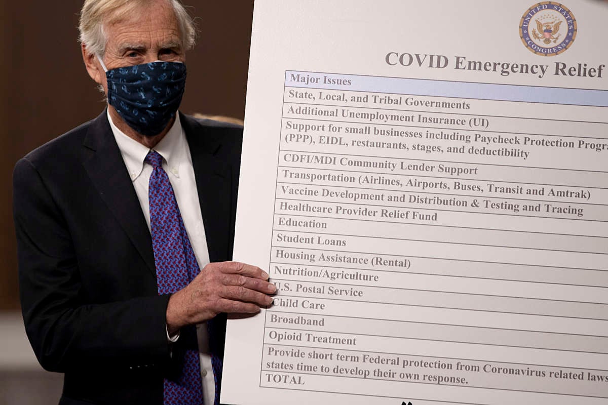 Sen. Angus King sets up a sign alongside a bipartisan group of Democrat and Republican members of Congress as they announce a proposal for a COVID-19 relief bill on Capitol Hill on December 1, 2020 in Washington, D.C.