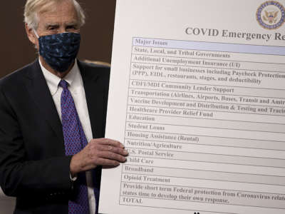 Sen. Angus King sets up a sign alongside a bipartisan group of Democrat and Republican members of Congress as they announce a proposal for a COVID-19 relief bill on Capitol Hill on December 1, 2020 in Washington, D.C.