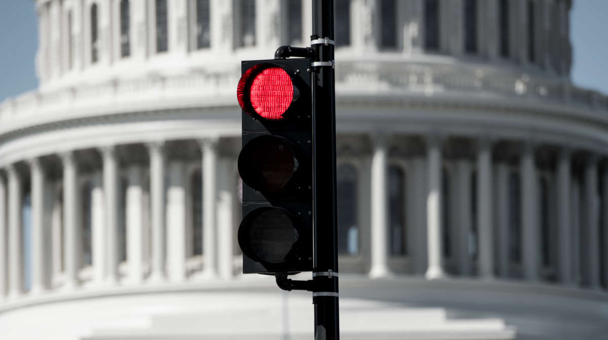 A red stoplight in front of the U.S. Capitol Building.