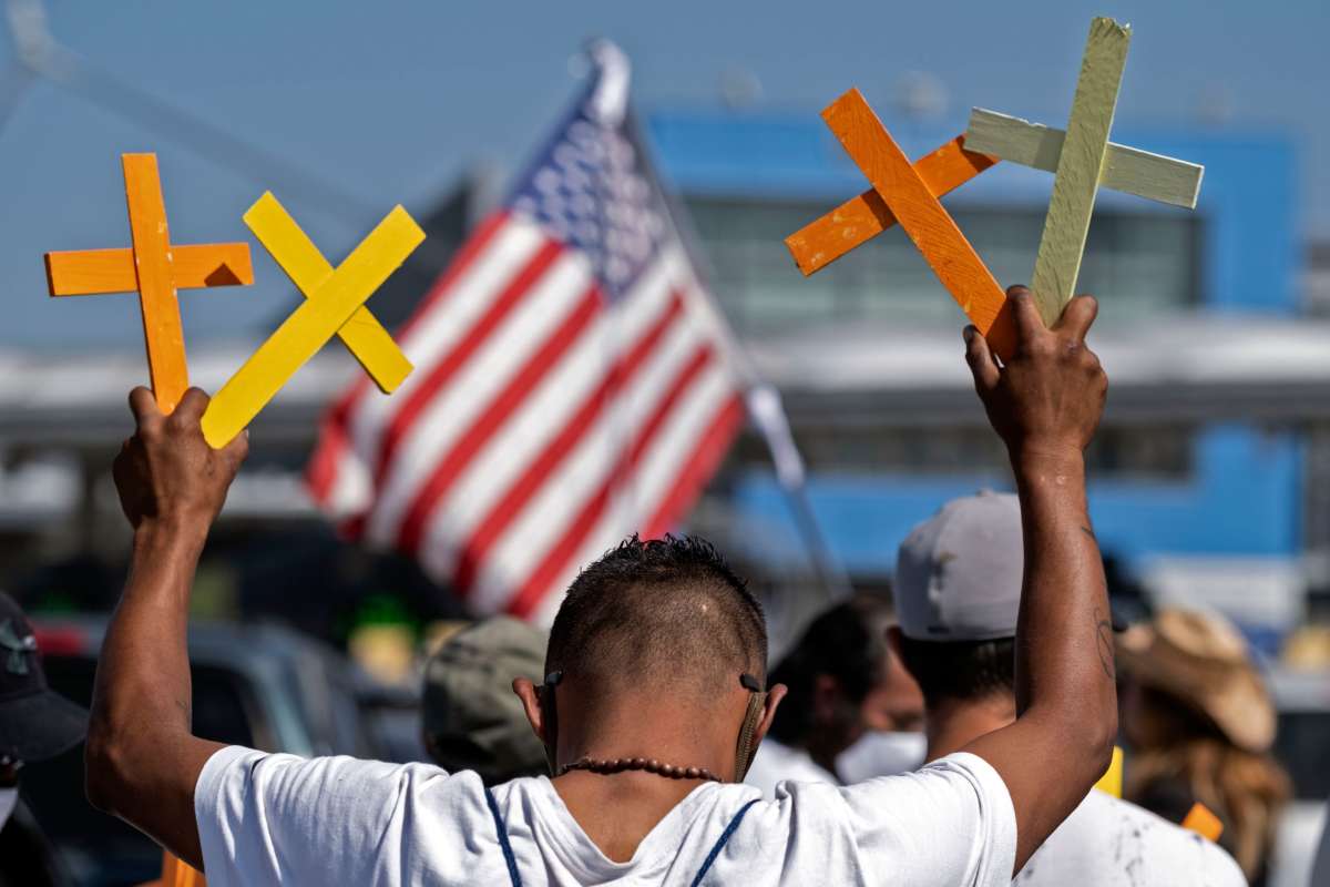 A man holds up four crosses