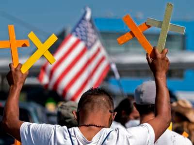 A man holds up four crosses