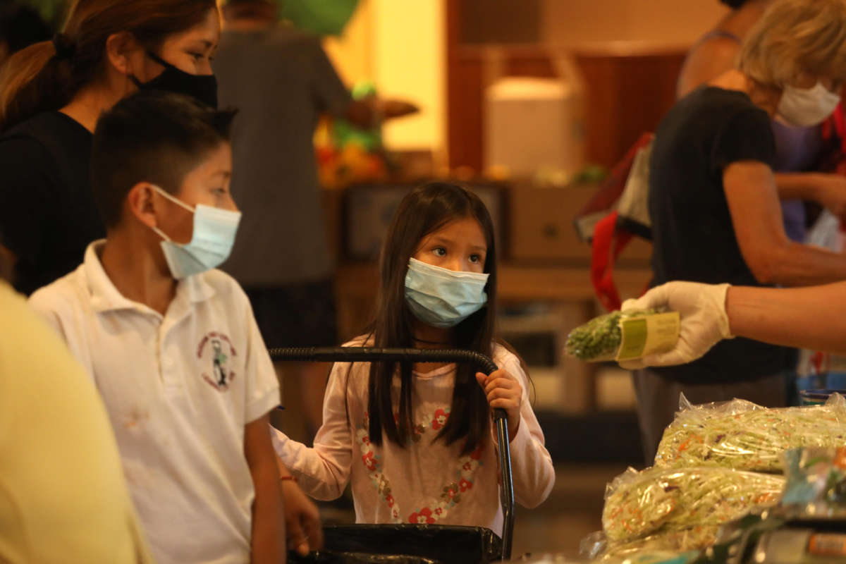 A volunteer talks with a young girl at the weekly food giveaway in the Fellowship Hall at Valley Park Church in North Hills, California, on October 14, 2020.