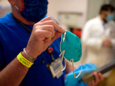 A health care worker holds up an N95 mask in the ER at Oakbend Medical Center in Richmond, Texas, on July 15, 2020.