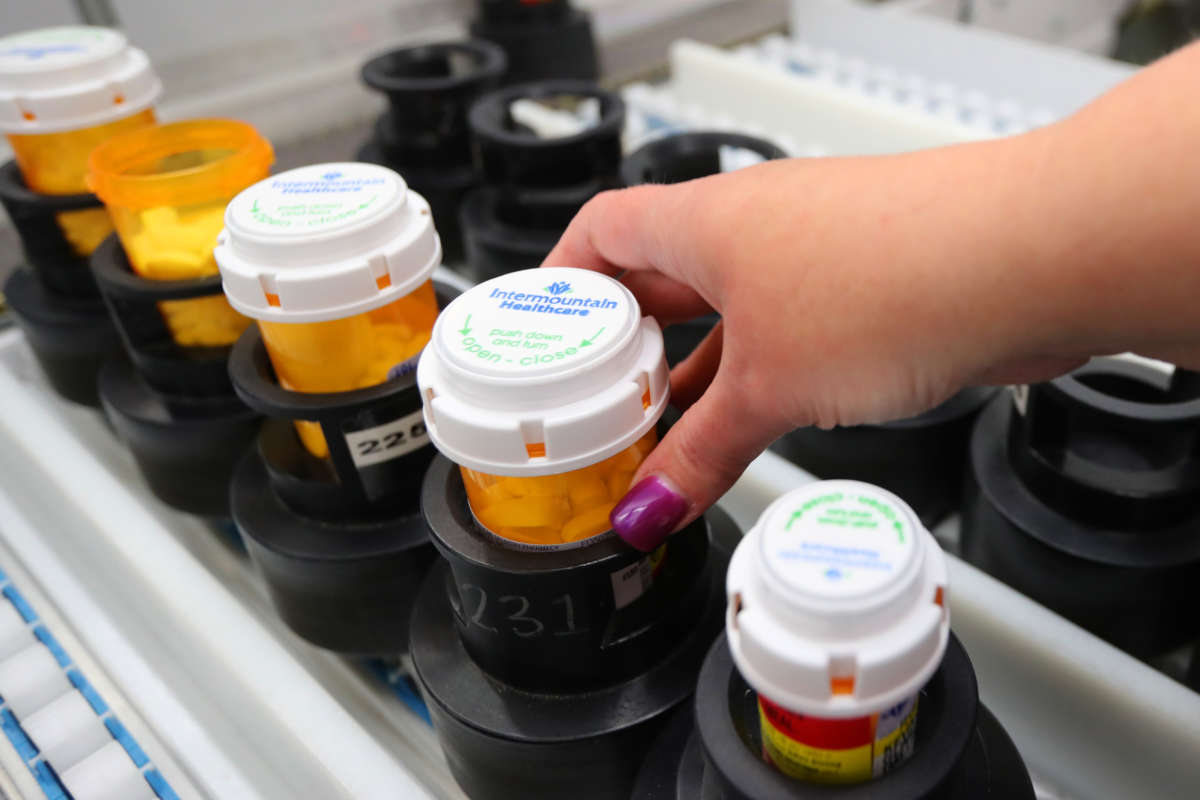 A hand with manicured nails adjusts a perscription bottle