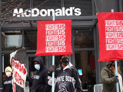 Protestors hold signs saying "Fight for $15" in front of McDonald's corporate headquarters.