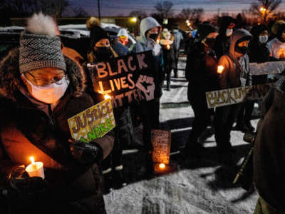 People hold Black Lives Matter signs as they gather during a candlelight vigil to honour Andre Hill's memory outside the Brentnell Community Recreation Center in Columbus, Ohio, on December 26, 2020.