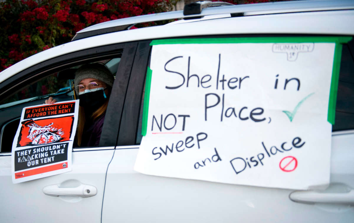 Activists with Services Not Sweeps place signs on their vehicles for a car blockade before Los Angeles City Bureau of Sanitation workers conduct a cleanup sweep of a homeless encampment during the COVID-19 pandemic on January 28, 2021, in Los Angeles, California.