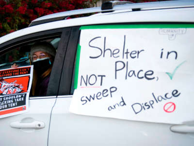 Activists with Services Not Sweeps place signs on their vehicles for a car blockade before Los Angeles City Bureau of Sanitation workers conduct a cleanup sweep of a homeless encampment during the COVID-19 pandemic on January 28, 2021, in Los Angeles, California.