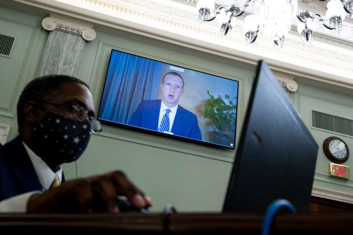 CEO of Facebook Mark Zuckerberg appears on a monitor behind a stenographer as he testifies remotely during a Senate Commerce, Science, and Transportation Committee hearing on Capitol Hill, October 28, 2020, in Washington, D.C.