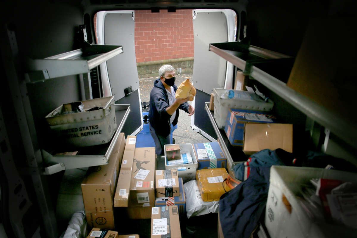 A postal worker puts mail into a truck