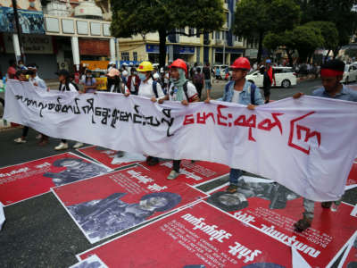 Myanmar protesters hold a huge poster as they march during a demonstration against the military coup near Sule Pagoda in central Yangon, Myanmar, on February 22, 2021.