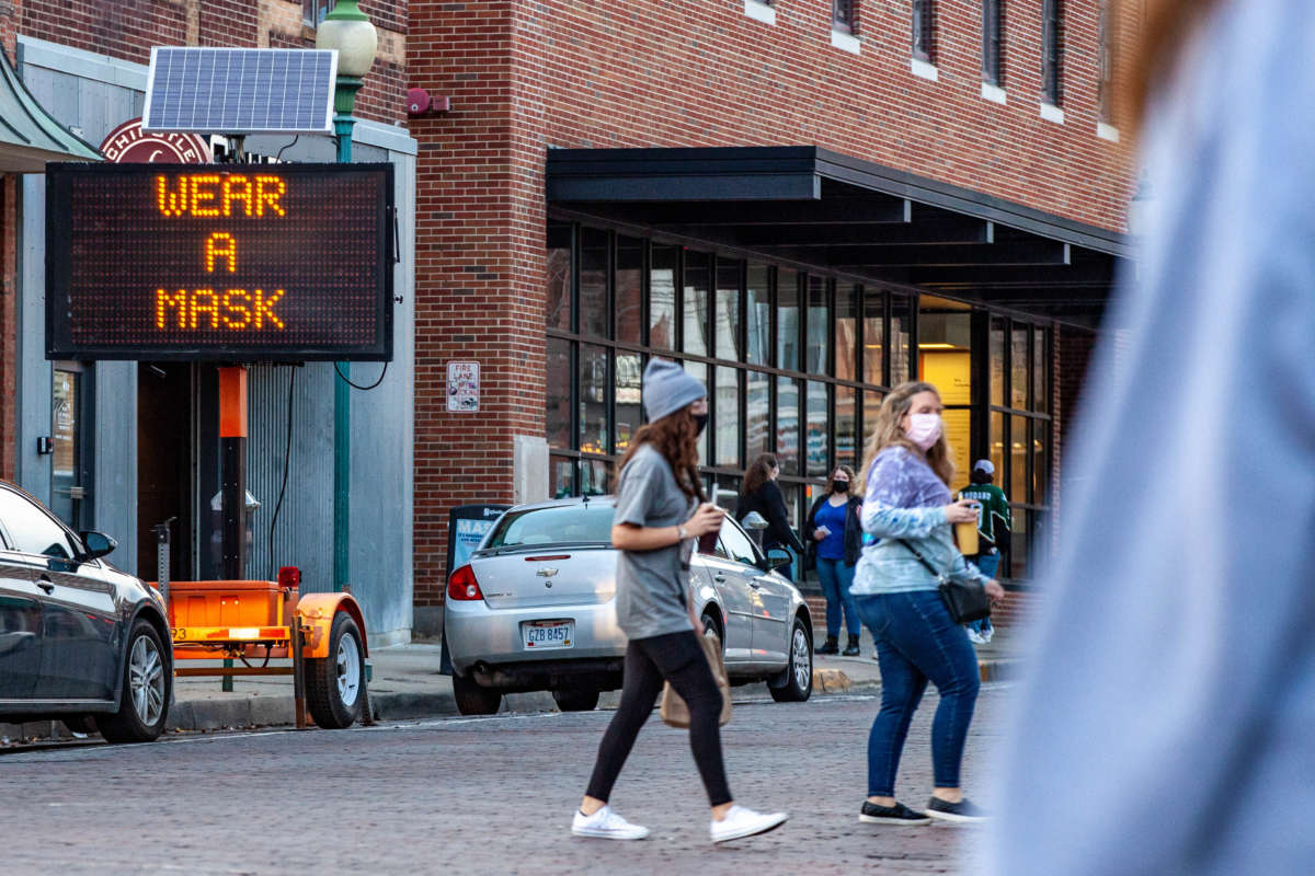 A public sign reads "wear a mask" as people cross the street in Athens, Ohio, on February 27, 2021.