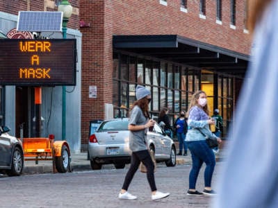 A public sign reads "wear a mask" as people cross the street in Athens, Ohio, on February 27, 2021.