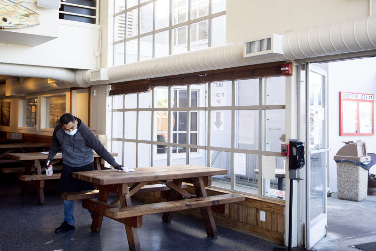 A restaurant worker disinfects indoor tables for customers waiting for to-go orders after resuming outdoor dining services at a restaurant in Sausalito, California, on, January 25, 2021.