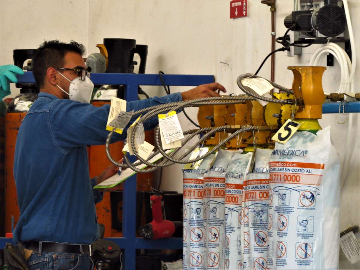 An INFRA worker refills an oxygen tank.