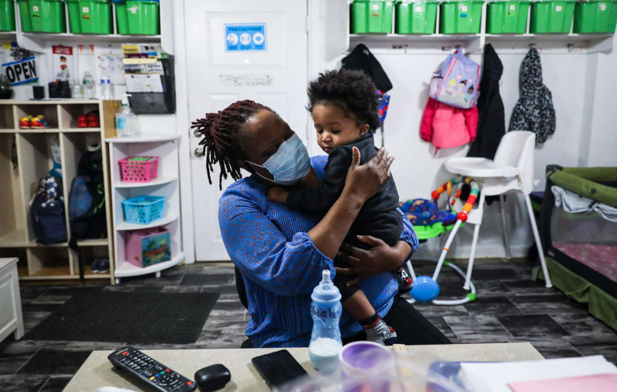 Kiddies Corner daycare owner Anne Osula holds a child before putting him down for a nap at the daycare in Boston's Mattapan on February 12, 2021.