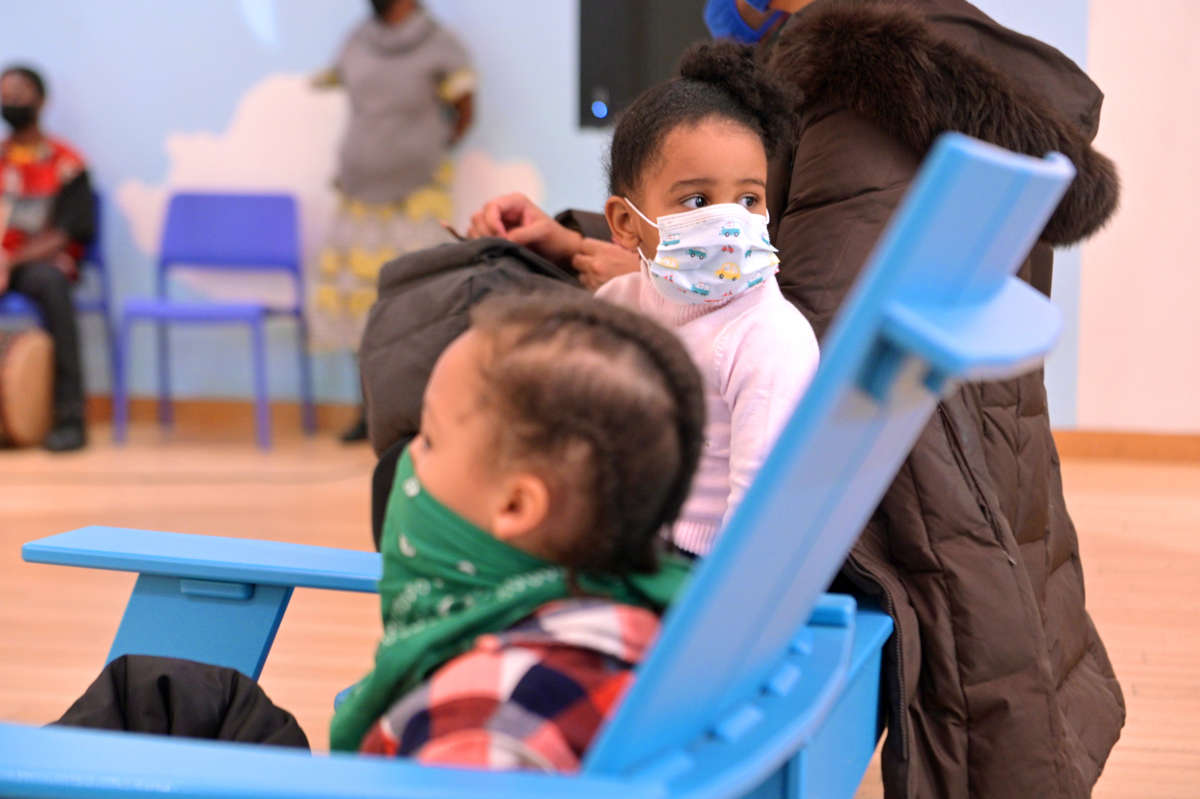 Masked children sit together in a room