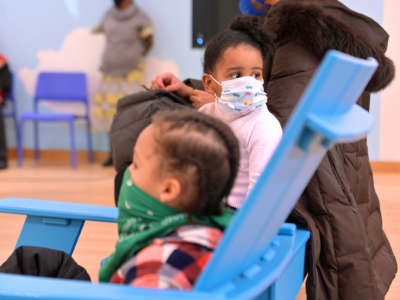 Masked children sit together in a room