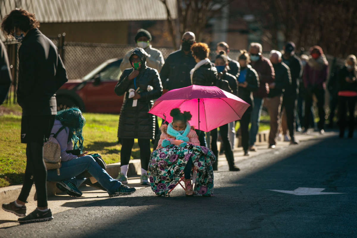 Voters wait in a long line to vote at the Buckhead library in Atlanta on the first day of in-person early voting for the Georgia Senate runoff election on December 14, 2020, in Atlanta, Georgia.