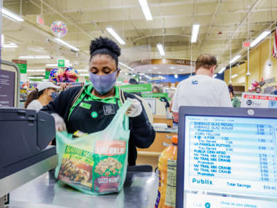 A cashier bags items at a Publix supermarket in Miami Beach, Florida, on May 27, 2020. In December 2020, Publix cosponsored a conference for legislators and corporate executives to discuss legal immunity from COVID-19 lawsuits.