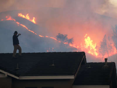A resident watches the brushfire at Chino Hills State Park from the roof of his house on October 27, 2020, in Chino Hills, California.
