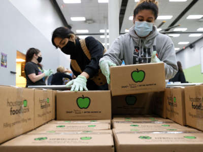 Volunteers stack emergency distribution boxes on a pallet at the Houston Food Bank on February 20, 2021, in Houston, Texas.