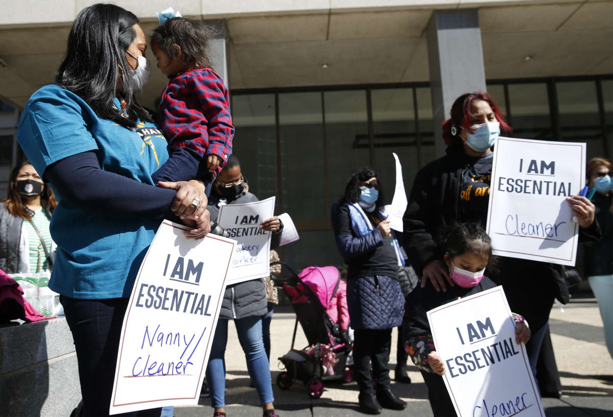 Masked domestic and childcare workers display signs during a protest