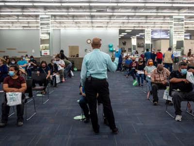 A worker calls out a time for some patients to be able to leave after being vaccinated at a vaccination site at a senior center on March 29, 2021, in San Antonio, Texas.