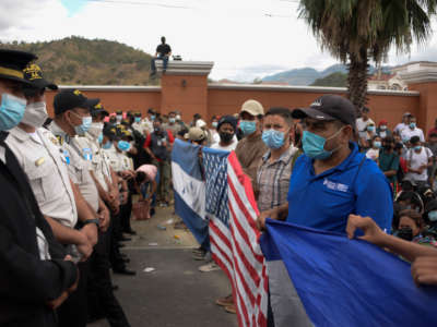 Honduran migrants, part of a caravan heading to the United States, stand in front of a police cordon, in Vado Hondo, Guatemala, on January 17, 2021.