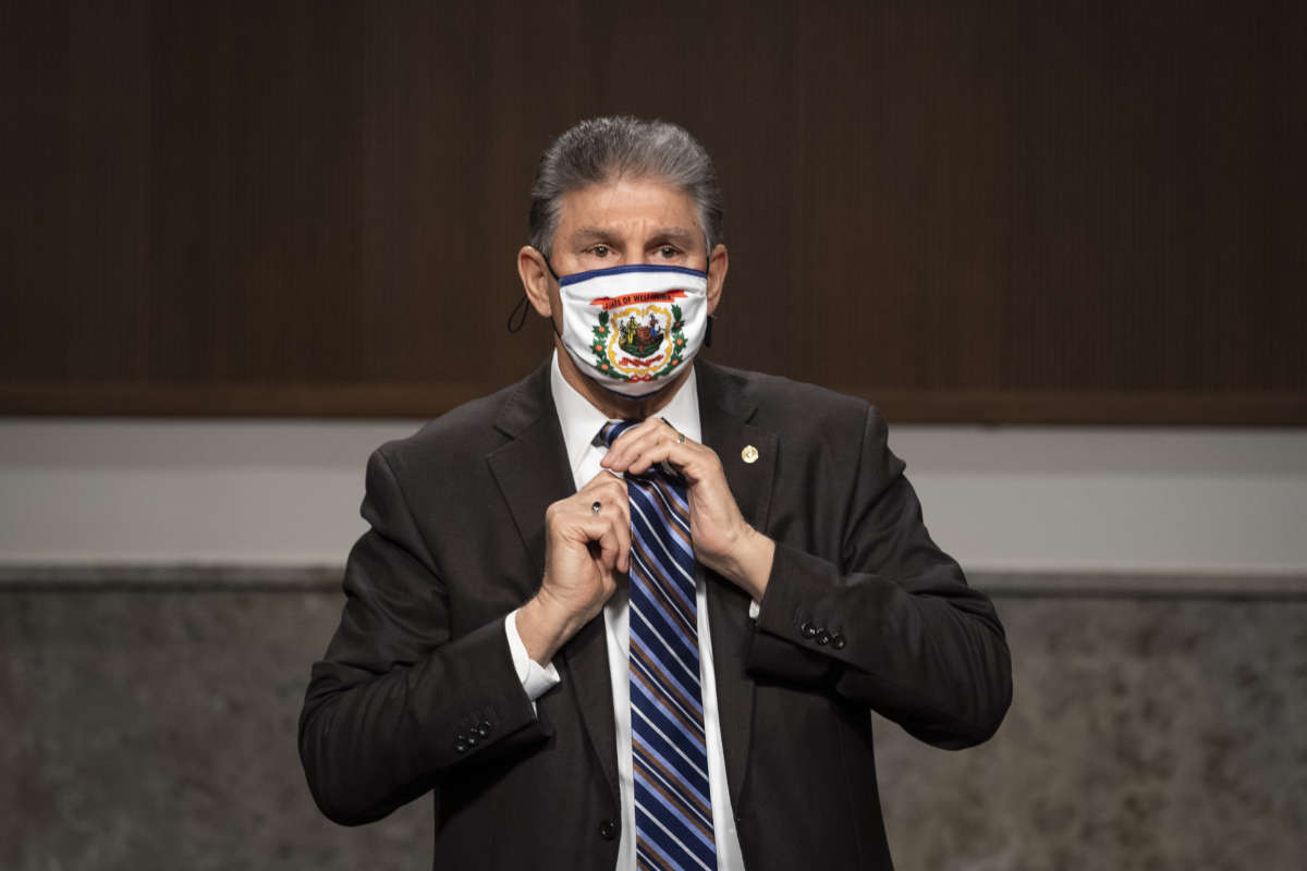 Sen. Joe Manchin adjusts his tie on March 4, 2021.