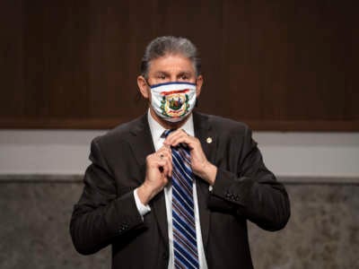 Sen. Joe Manchin adjusts his tie on March 4, 2021.