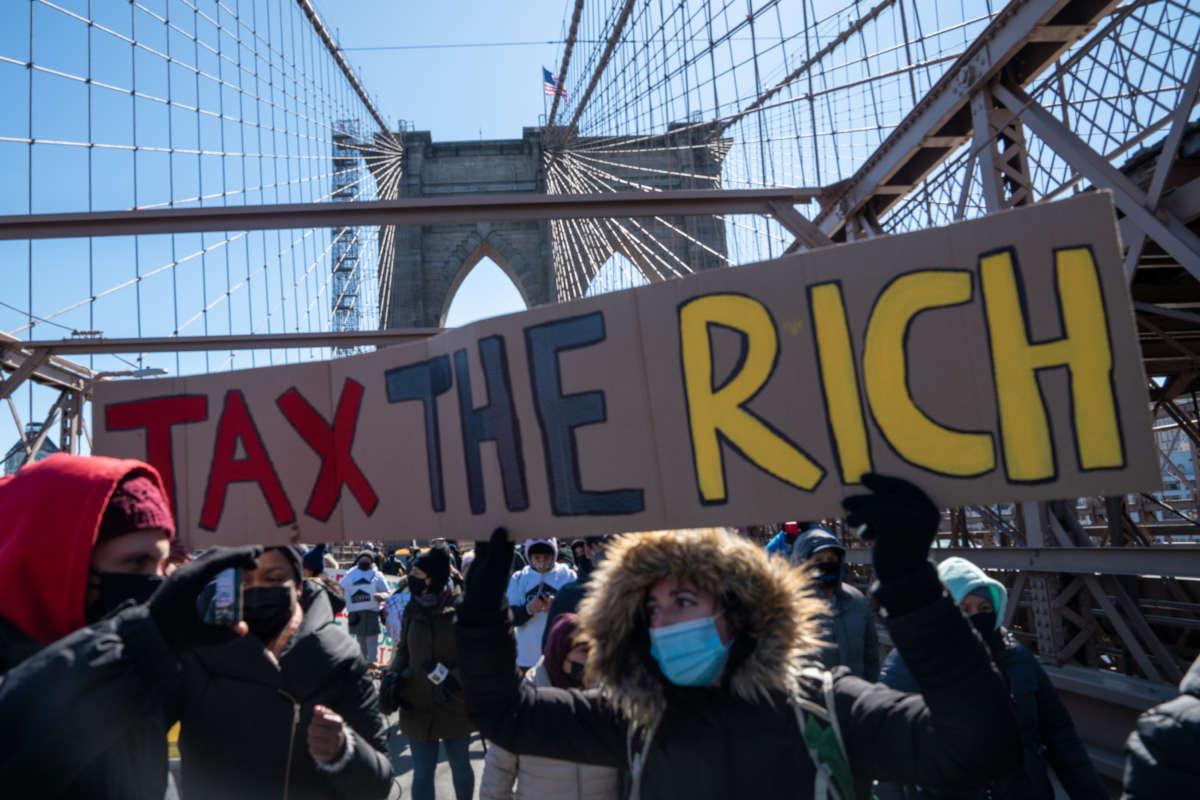 Protestors march across the Brooklyn Bridge holding a sign to "tax the rich" to demand funding for excluded workers in the New York State budget on March 5, 2021, in New York City.