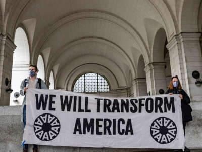 Activists display a banner reading "WE WILL TRANSFORM AMERICA"