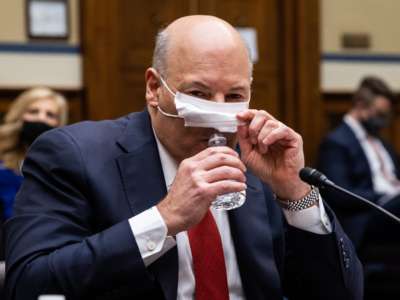 Louis DeJoy lifts his mask to sip water from a bottle in perhaps the most sinister looking way possible