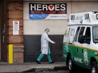 A medical worker walks by ambulances outside of a hospital