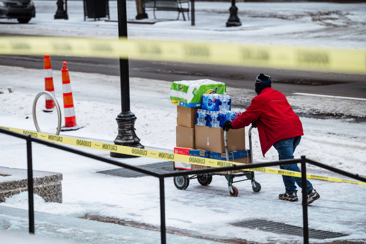 A person wheels a cart full of food down a frozen sidewalk