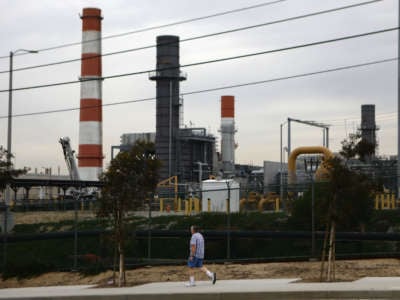 A man walks past a power plant looming in the background