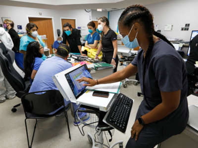 Medical students and staff members on the COVID-19 ward at United Memorial Medical Center gather to go over patients' status at the start of their shift on July 1, 2020.