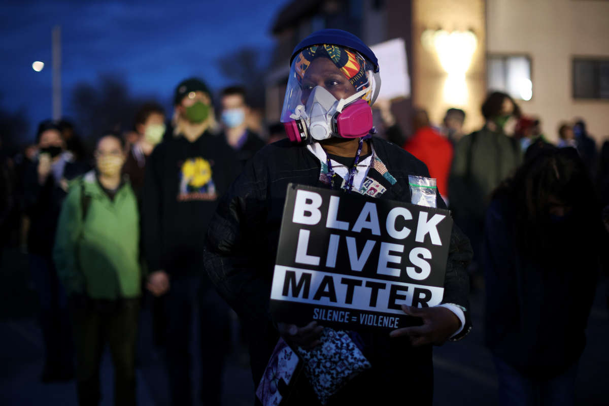 A protester in a mask holds a Black Lives Matter sign