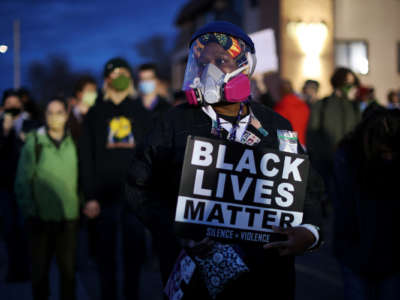 A protester in a mask holds a Black Lives Matter sign