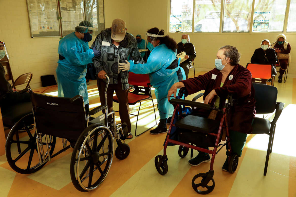 After receiving a Moderna COVID-19 vaccine, Ana Canales, 78, right, watches as the next elderly recipient is helped to his seat at Clinica Romero in Los Angeles on February 6, 2021.