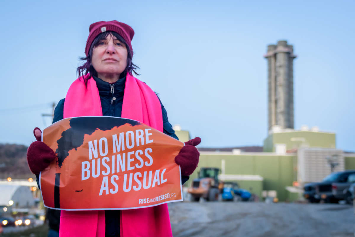 A protester holds a sign reading "NO MORE BUSINESS AS USUAL"