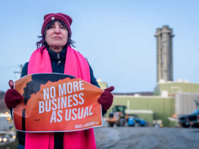 A protester holds a sign reading "NO MORE BUSINESS AS USUAL"