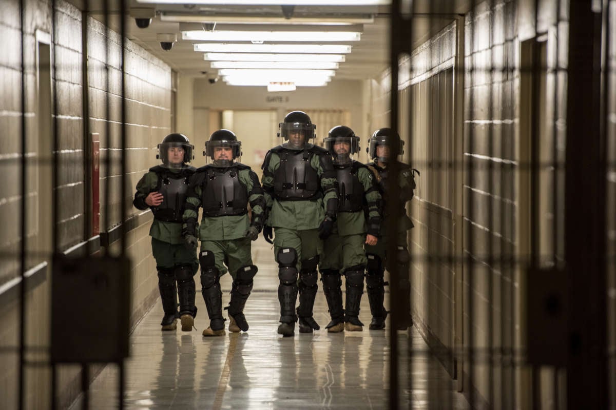 An Office of Enforcement and Removal Operations Special Response Team walks through a detention facility in riot gear.